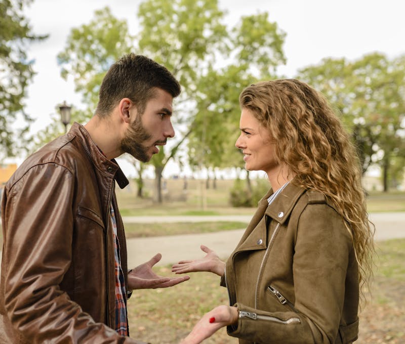 A couple having an argument outdoors, expressing frustration and conflict.