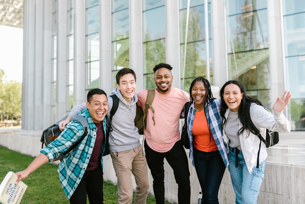 A happy group of diverse college students posing cheerfully outside a modern building.