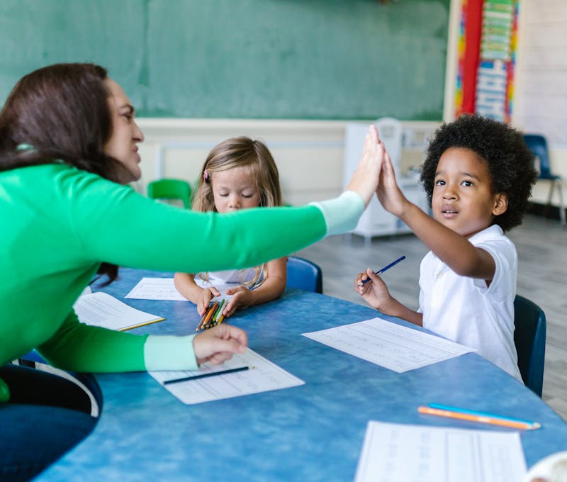 A teacher and students enjoying a high five during a classroom learning activity.