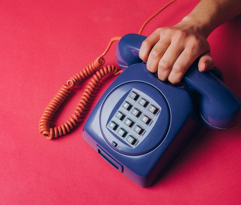 Close-up of a hand holding a vintage blue telephone, evoking nostalgia and retro vibes.