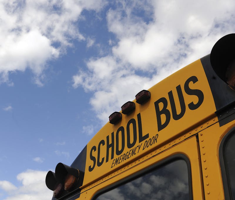 Close-up shot of a yellow school bus with a blue sky background, showcasing cloud formations.