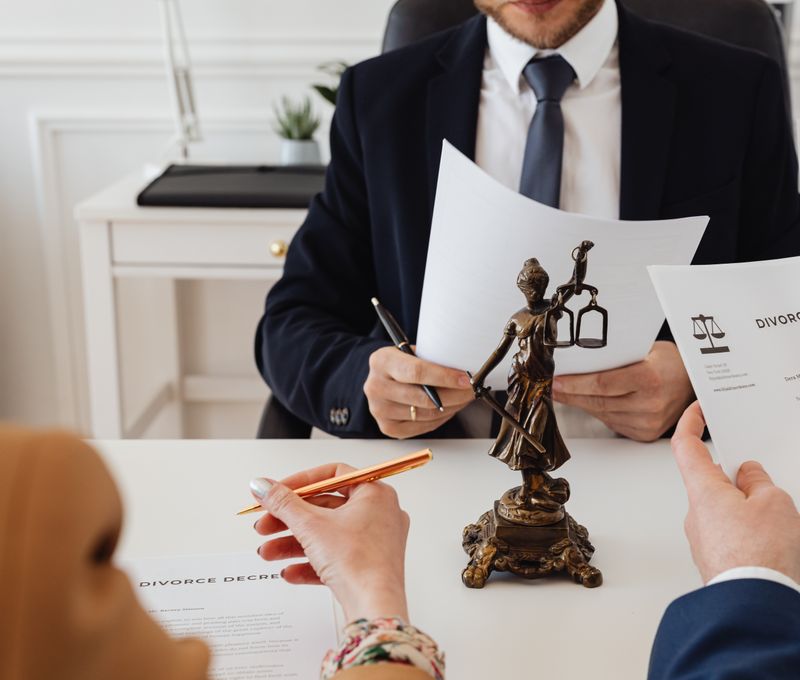 Legal professionals reviewing divorce documents in a law office with a Lady Justice statue.