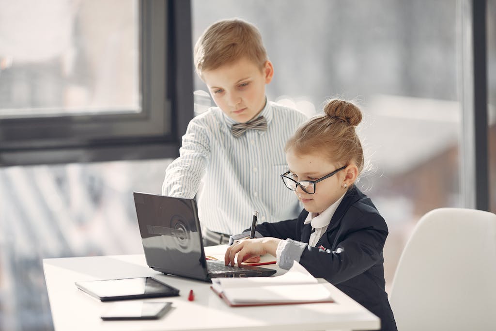 Professional little entrepreneurs with laptop in modern office