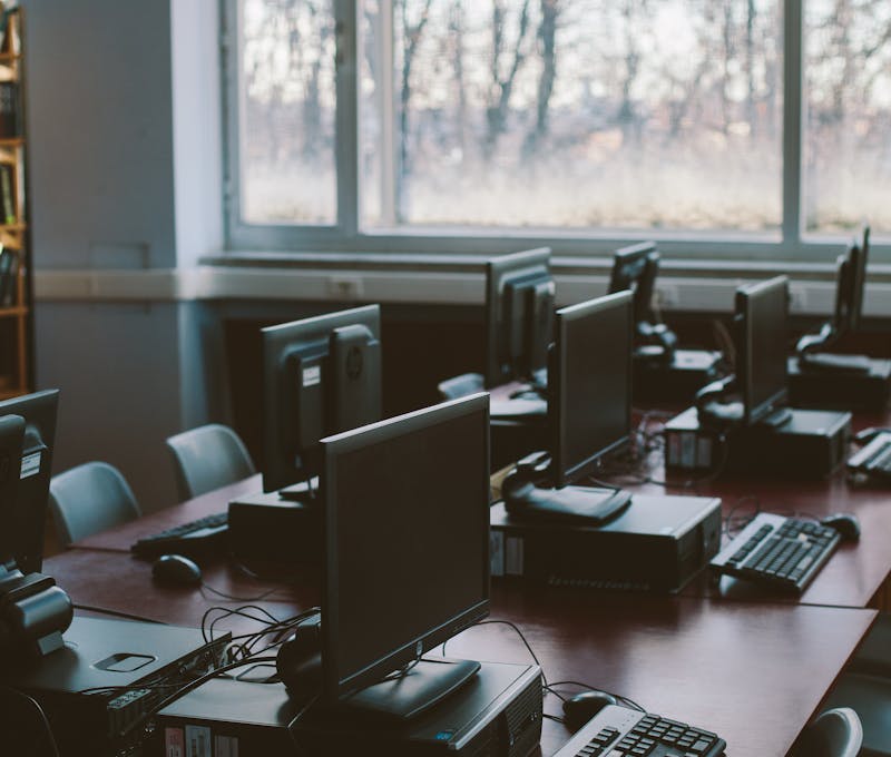 Spacious computer lab with rows of monitors and keyboards in a sunlit room.